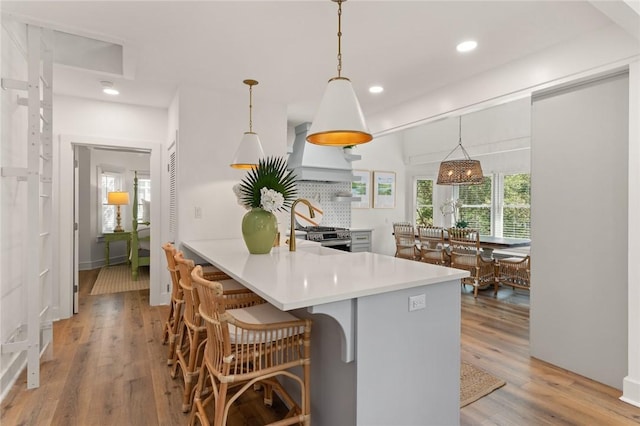 108 Hamilton St, Saint Simons Island, GA 31522 - kitchen with custom exhaust hood, light wood-type flooring, light countertops, a breakfast bar, and recessed lighting