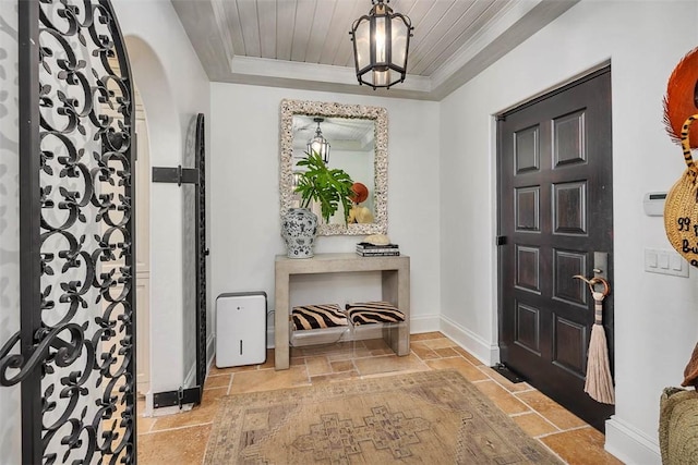 foyer entrance featuring a raised ceiling, wooden ceiling, and ornamental molding