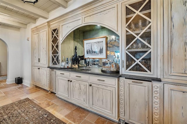 bar featuring beam ceiling, cream cabinets, sink, and wooden ceiling