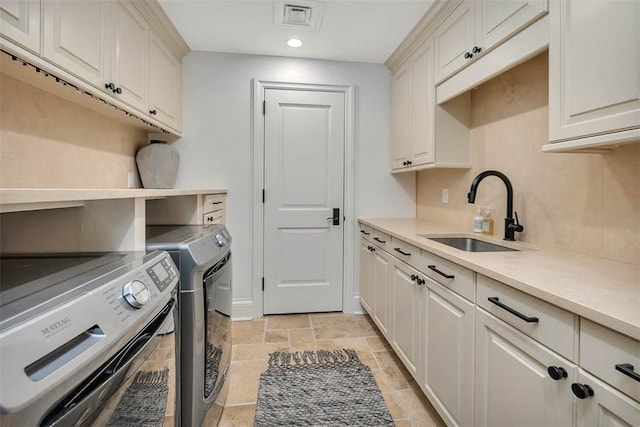 washroom featuring separate washer and dryer, sink, and cabinets