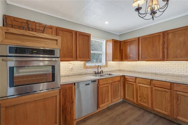 kitchen featuring dark wood-type flooring, a chandelier, decorative backsplash, stainless steel appliances, and a sink