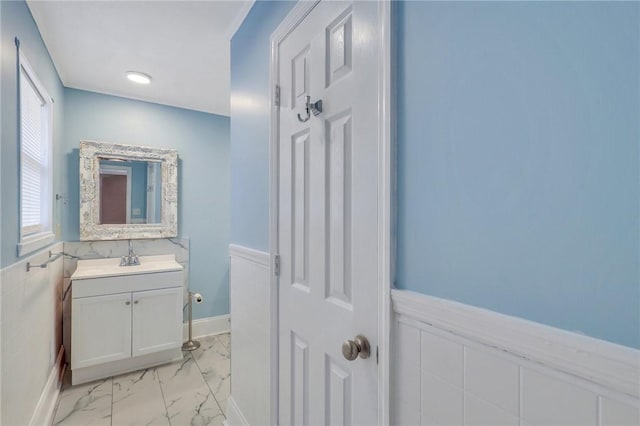 bathroom featuring a wainscoted wall, vanity, and marble finish floor