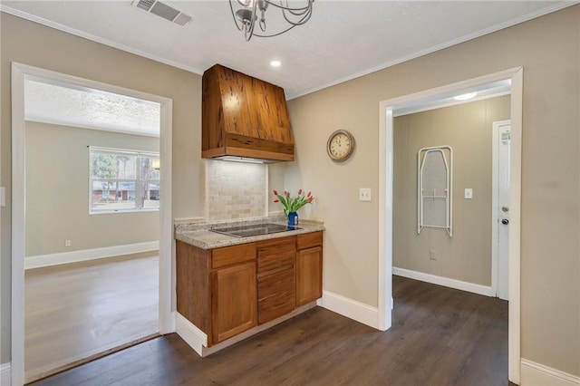 kitchen with premium range hood, visible vents, brown cabinets, dark wood finished floors, and black electric cooktop