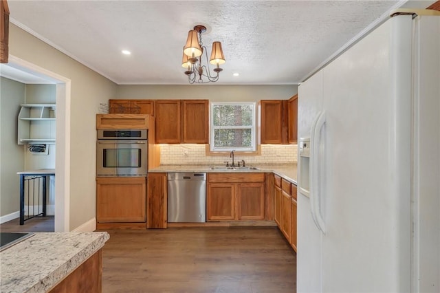 kitchen with tasteful backsplash, light countertops, appliances with stainless steel finishes, wood finished floors, and a sink