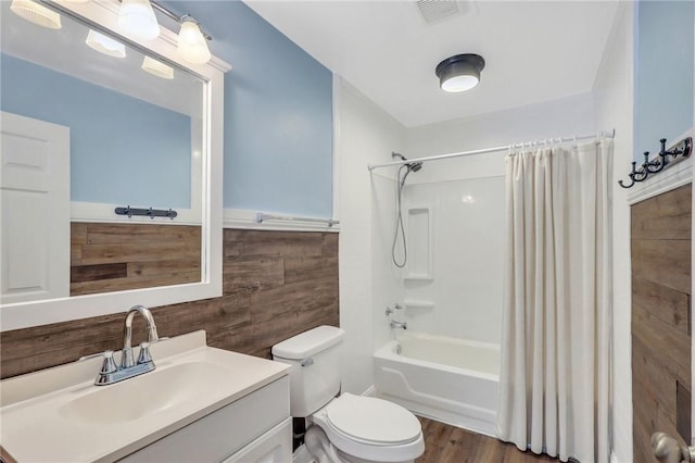 full bathroom featuring vanity, visible vents, shower / tub combo, wood walls, and toilet