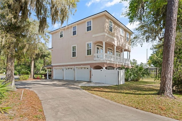 142 Montrose, Saint Simons Island, GA 31522 - view of home's exterior featuring an attached garage, stucco siding, a gate, driveway, and a balcony