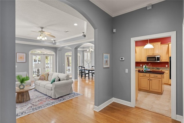 142 Montrose, Saint Simons Island, GA 31522 - living room with arched walkways, light wood-type flooring, a ceiling fan, crown molding, and a chandelier