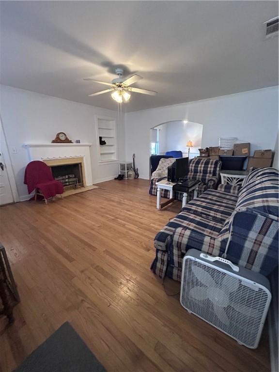 1401 Carswell Ave, Waycross, GA 31501 - living area featuring wood finished floors, ceiling fan, built in features, and a fireplace with flush hearth