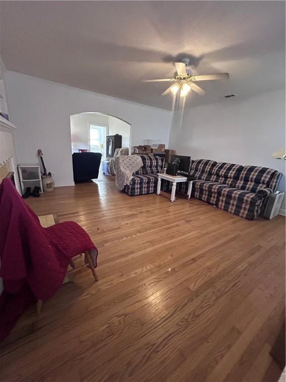 living room with ceiling fan, visible vents, arched walkways, and wood finished floors