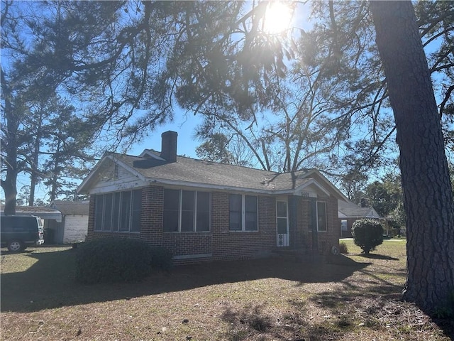 exterior space with brick siding, a chimney, and a lawn