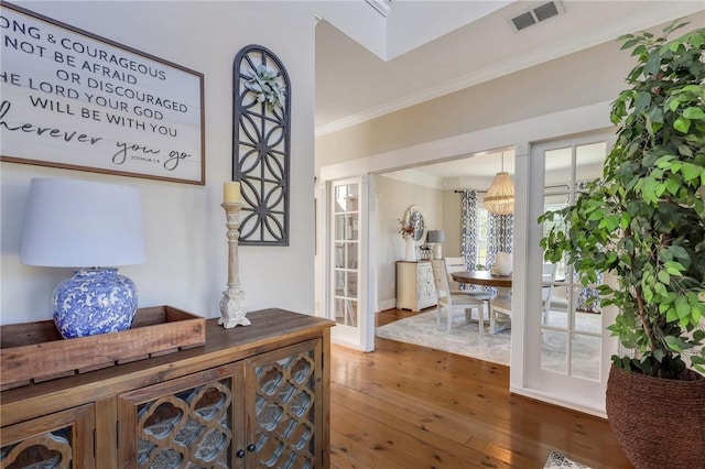 corridor with visible vents, hardwood / wood-style floors, and crown molding