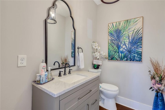 half bath featuring baseboards, toilet, and vanity