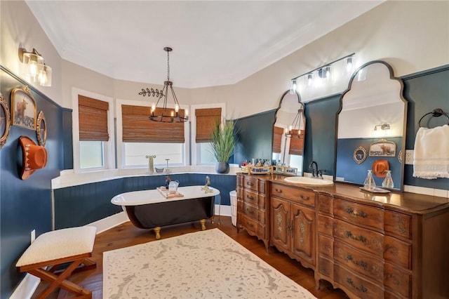 full bathroom with a freestanding bath, vanity, an inviting chandelier, and wood finished floors