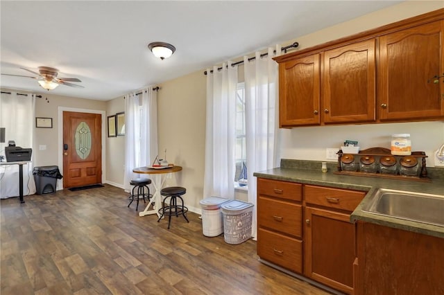 kitchen with dark wood-style floors, brown cabinets, dark countertops, and a ceiling fan