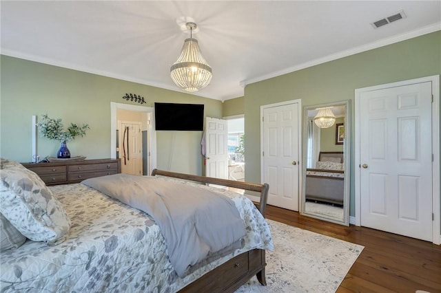 bedroom featuring visible vents, dark wood finished floors, connected bathroom, an inviting chandelier, and crown molding