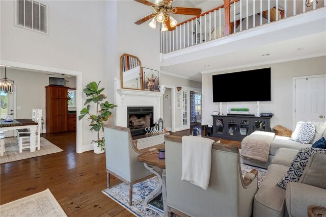 living room featuring visible vents, a fireplace with raised hearth, plenty of natural light, and wood-type flooring