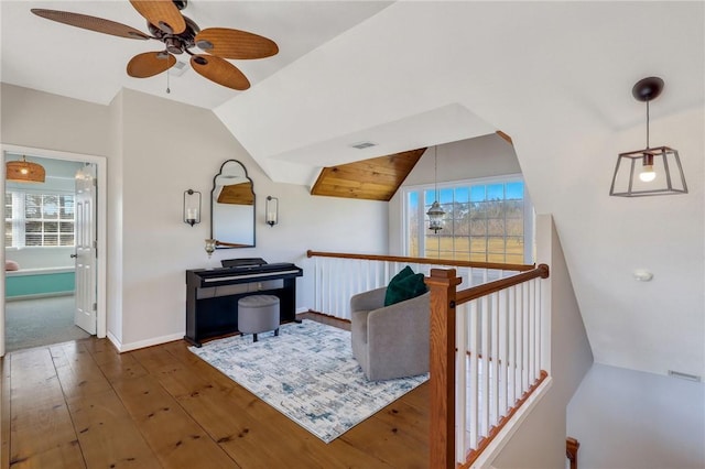 interior space with an upstairs landing, visible vents, hardwood / wood-style flooring, and vaulted ceiling