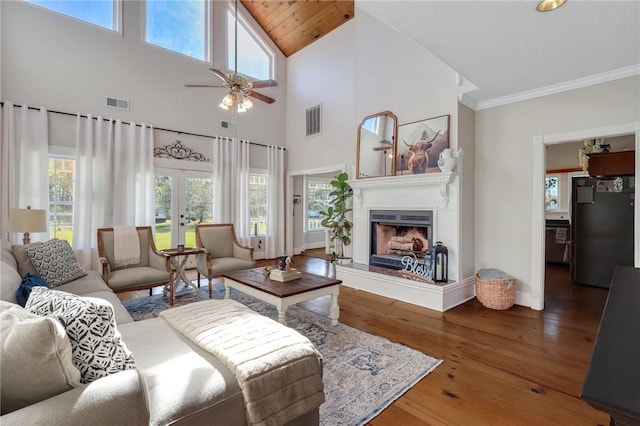 living area with hardwood / wood-style floors, french doors, visible vents, and a fireplace with raised hearth