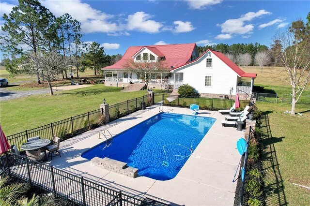 view of swimming pool featuring a patio area, a fenced in pool, a yard, and fence