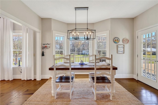 dining space with baseboards, wood-type flooring, and a chandelier