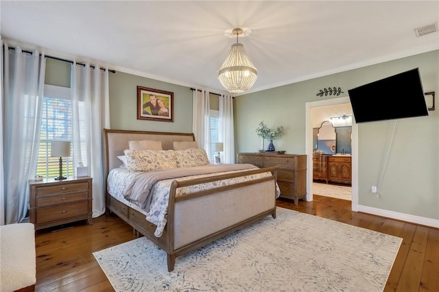 bedroom featuring visible vents, a notable chandelier, ensuite bathroom, hardwood / wood-style flooring, and crown molding