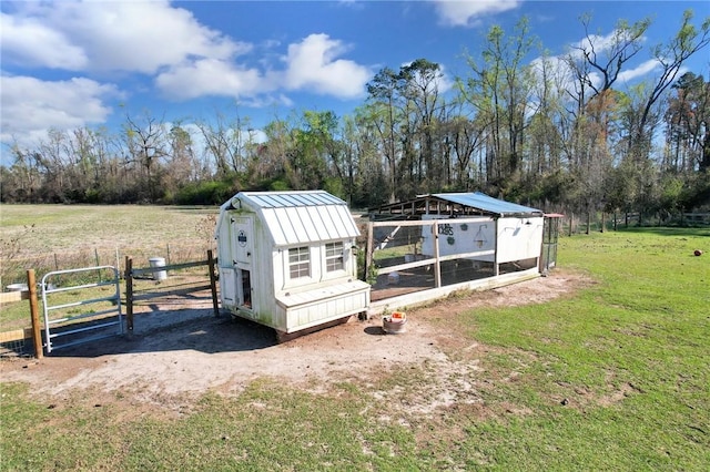 view of poultry coop with a rural view, a yard, and fence