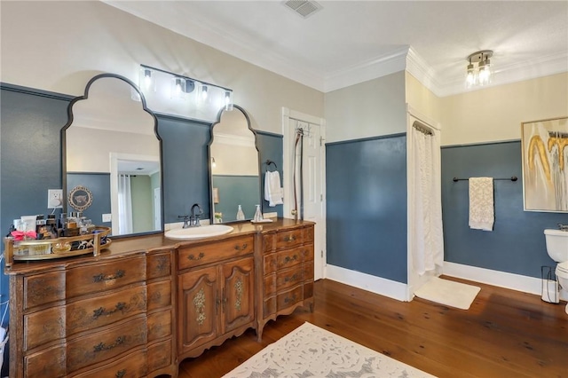 bathroom with visible vents, baseboards, ornamental molding, wood finished floors, and vanity