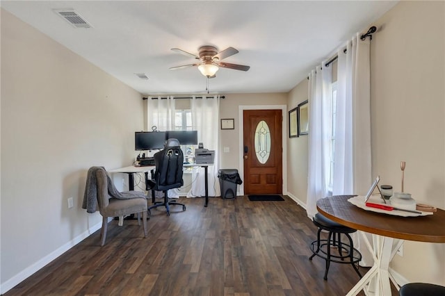 office area with dark wood finished floors, baseboards, visible vents, and a ceiling fan