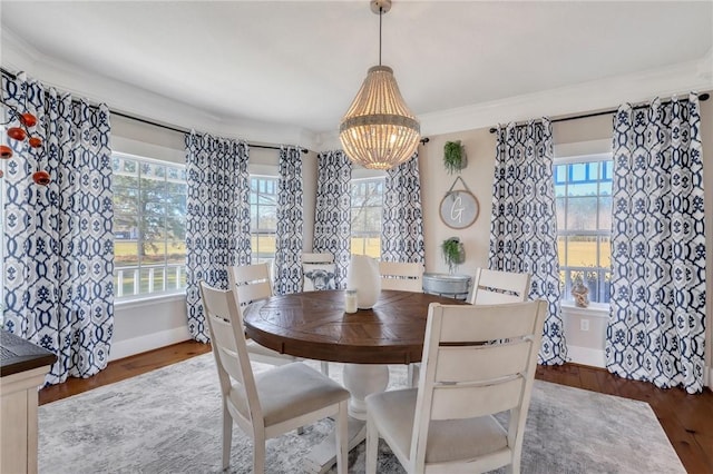 dining area featuring a notable chandelier, crown molding, baseboards, and wood finished floors