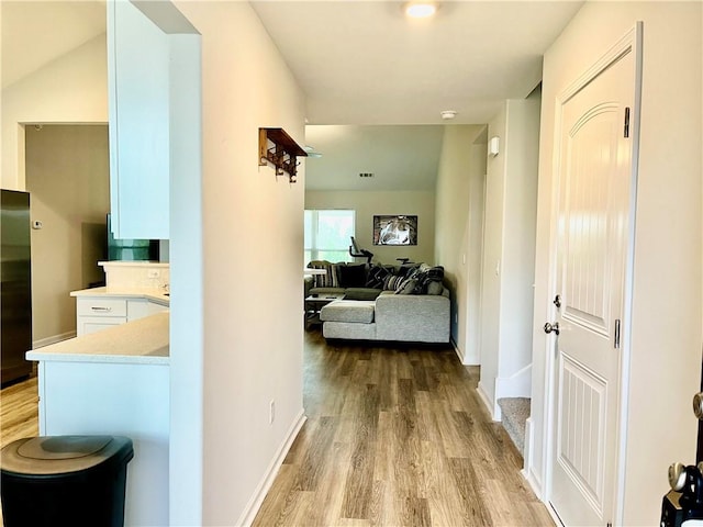 hall featuring light wood-style flooring and baseboards