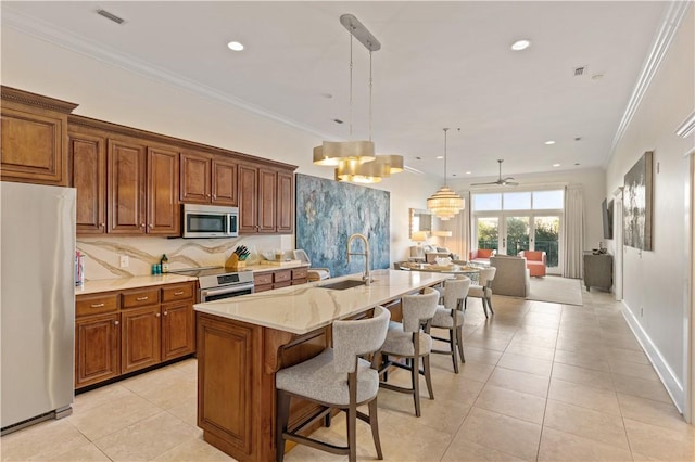 800 Ocean Blvd Unit 205, Saint Simons Island, GA 31522 - kitchen featuring sink, hanging light fixtures, a kitchen island with sink, appliances with stainless steel finishes, and ornamental molding