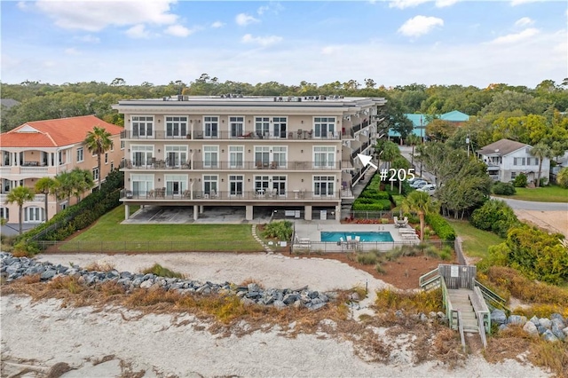 rear view of property featuring a community pool and a yard