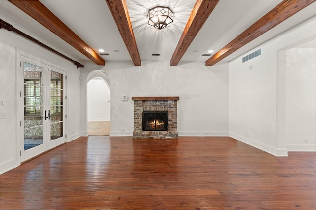 unfurnished living room featuring dark hardwood / wood-style floors, french doors, a brick fireplace, and beamed ceiling