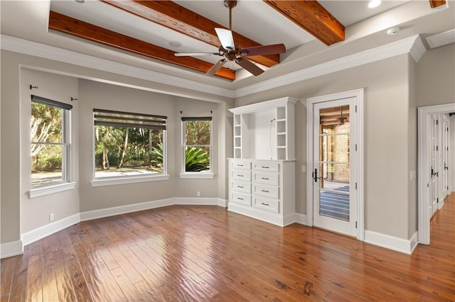 unfurnished bedroom featuring ceiling fan, wood-type flooring, beamed ceiling, and ornamental molding