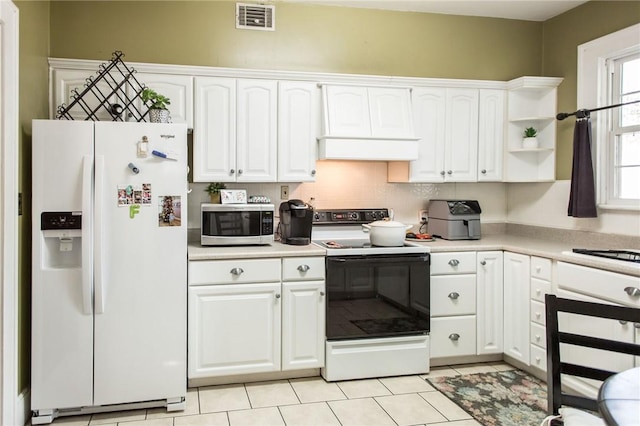 kitchen featuring stainless steel microwave, range with electric stovetop, white fridge with ice dispenser, visible vents, and white cabinets