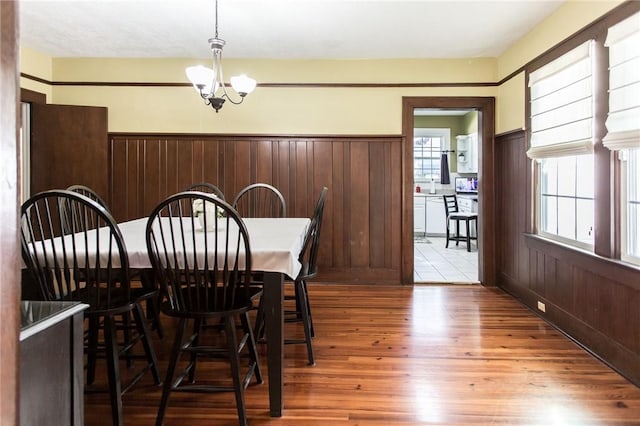 dining room with a wainscoted wall, a chandelier, plenty of natural light, and wood finished floors