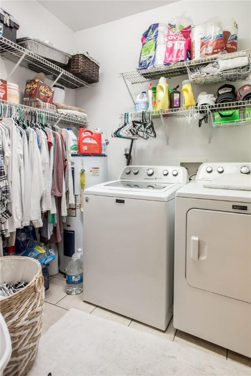 laundry room featuring light tile patterned floors, laundry area, washer and dryer, and gas water heater