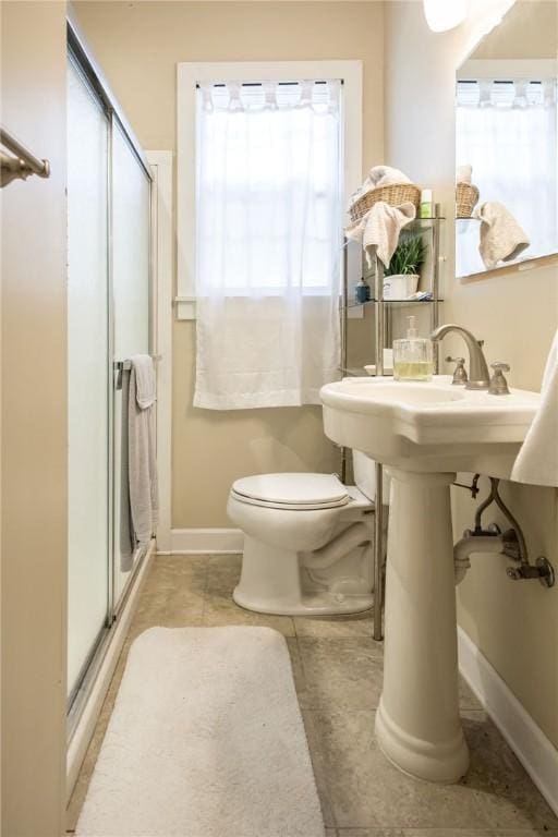 bathroom featuring tile patterned floors, toilet, baseboards, and a stall shower