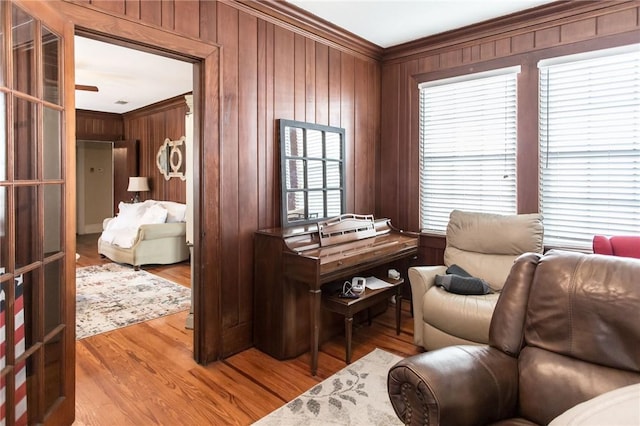 living area featuring ornamental molding, wooden walls, and wood finished floors