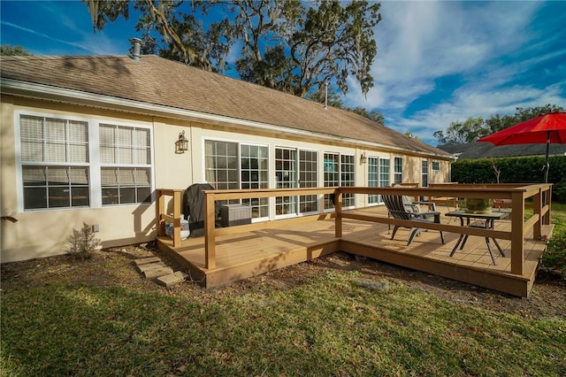 back of property featuring stucco siding, a wooden deck, and roof with shingles