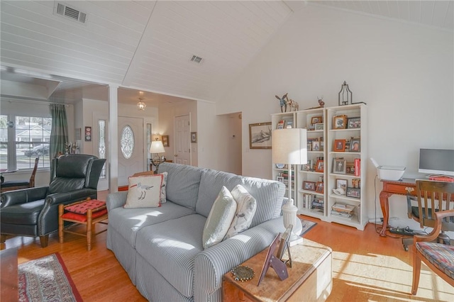 living area with visible vents, lofted ceiling, and wood finished floors