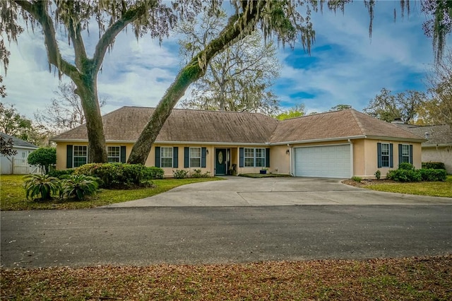 ranch-style home featuring a garage, driveway, and stucco siding