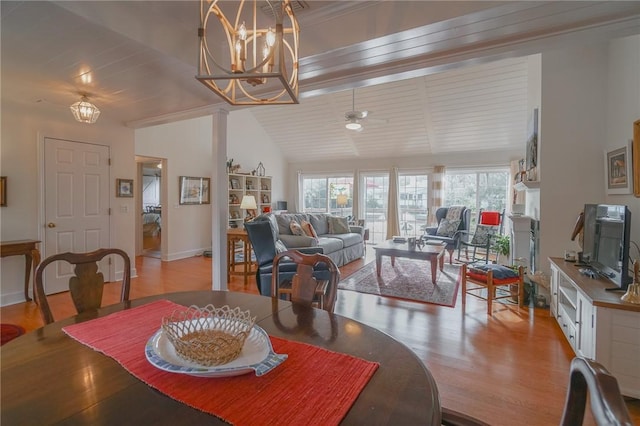 dining space featuring ceiling fan with notable chandelier, baseboards, lofted ceiling, and wood finished floors