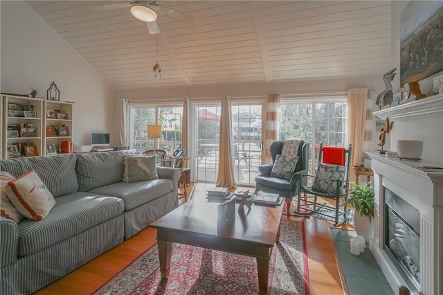 living area featuring lofted ceiling, a fireplace with flush hearth, a wealth of natural light, and ceiling fan