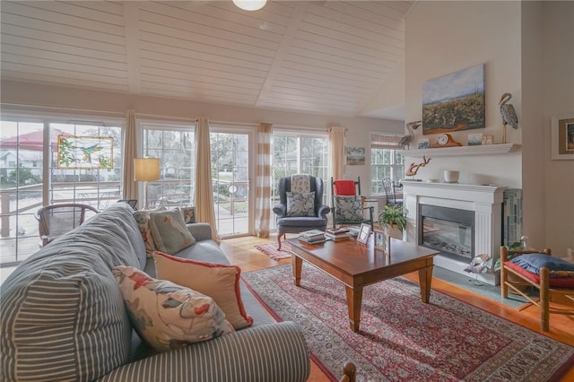 living room featuring a glass covered fireplace, beamed ceiling, high vaulted ceiling, and wood finished floors