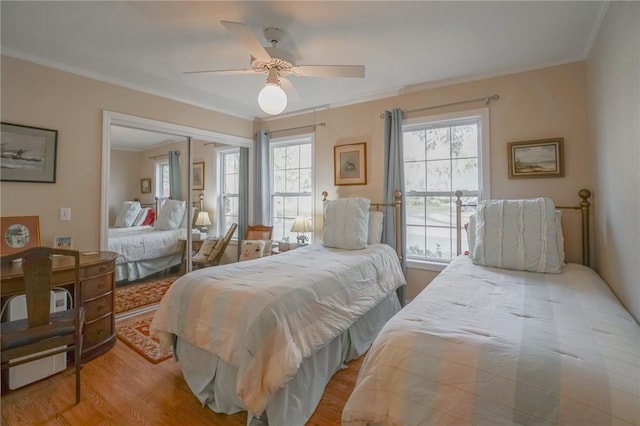 bedroom featuring a closet, wood finished floors, ceiling fan, and ornamental molding