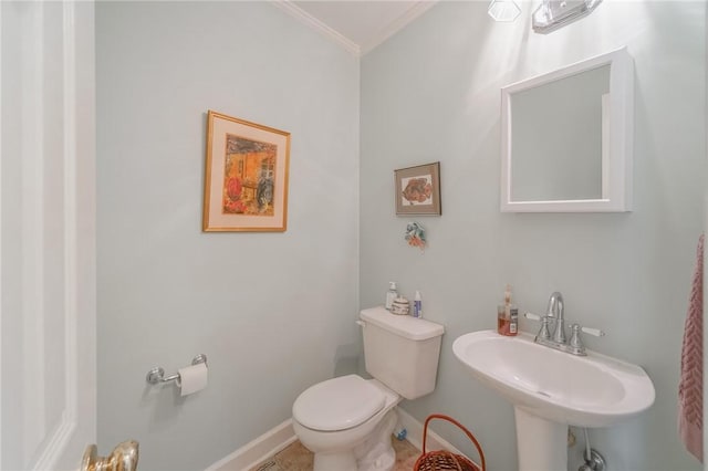 half bathroom featuring a sink, baseboards, toilet, and ornamental molding