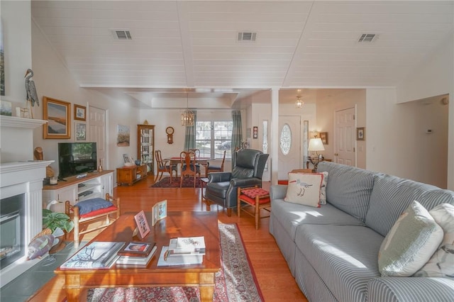 living area with light wood finished floors, visible vents, and vaulted ceiling with beams