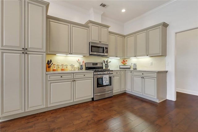 kitchen featuring dark wood-style floors, light countertops, decorative backsplash, appliances with stainless steel finishes, and ornamental molding