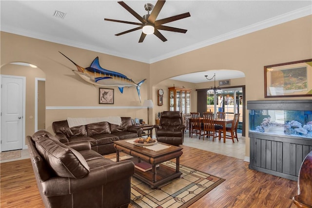 living room with ceiling fan with notable chandelier, wood-type flooring, and ornamental molding